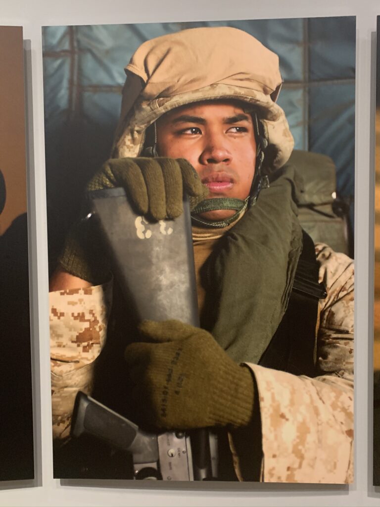 Portrait of a young man in military uniform, hands resting on the butt of a rifle, ©Stacy Pearsall